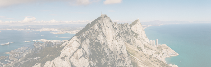 Scenic landscape photography of the Rock of Gibraltar peak and surrounding coastline, showing the Strait of Gibraltar and the Iberian Peninsula.