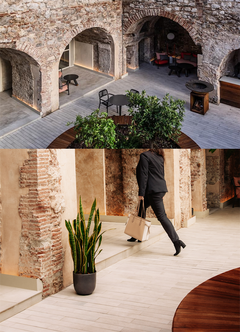 Boutique hotel courtyard architecture combining historic stone ruins with modern luxury interior design. Displays an outdoor lounge area nestled under ancient brick arches alongside a professional guest walking through a contemporary tiled corridor.