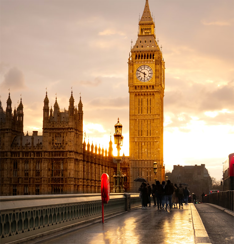 Iconic London landmark photography featuring Big Ben and the Houses of Parliament at sunset. The scenic view captures the historic Gothic architecture glowing in warm evening light from across Westminster Bridge.