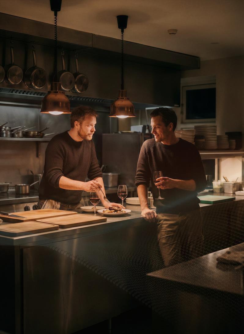 Professional chefs evaluating a signature gourmet dish in a commercial kitchen environment. The atmosphere highlights fine dining culinary development, kitchen teamwork, and premium hospitality lifestyles during an evening dinner service.